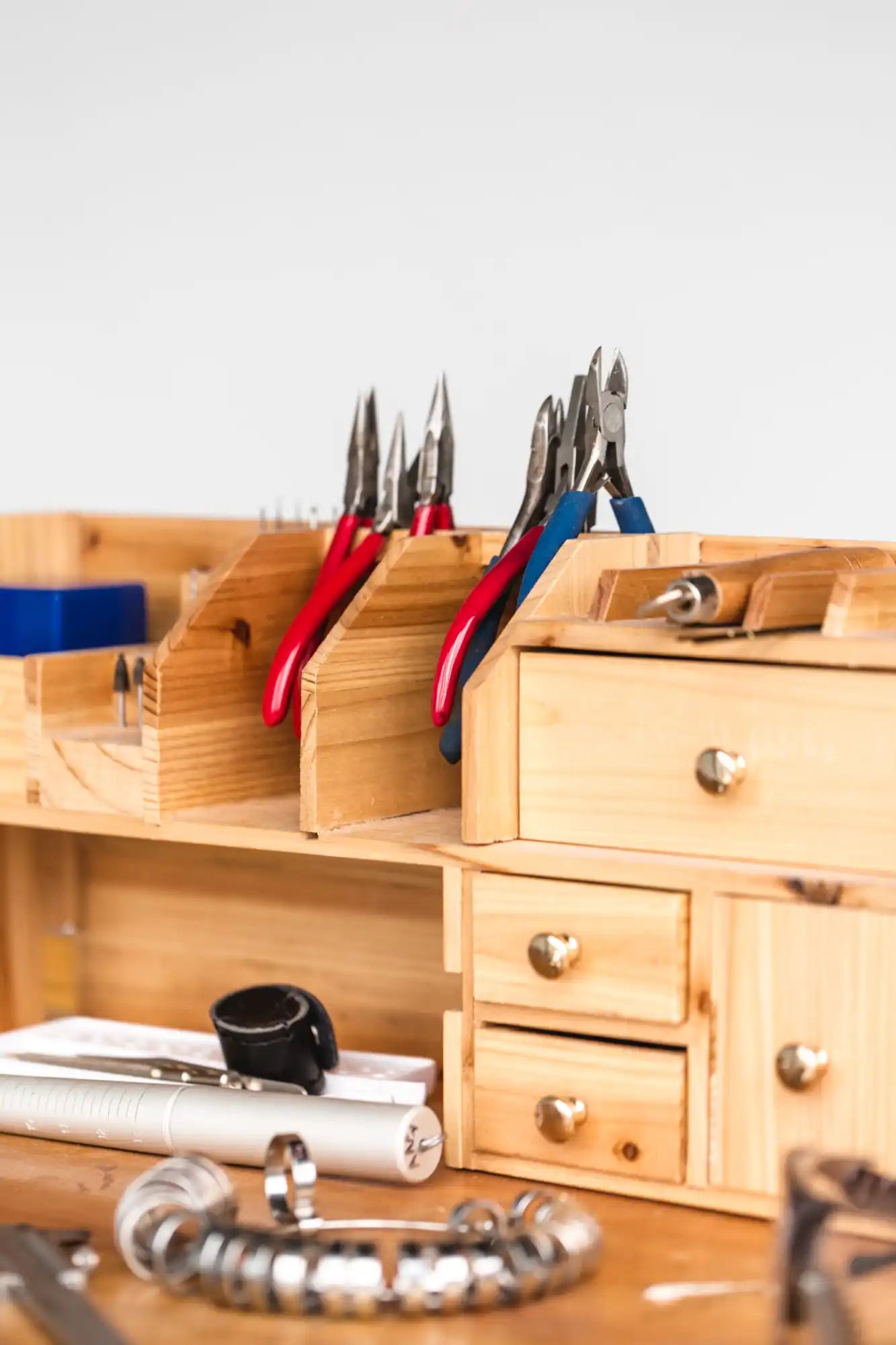 A wooden jewelry-making workstation with various tools and supplies.