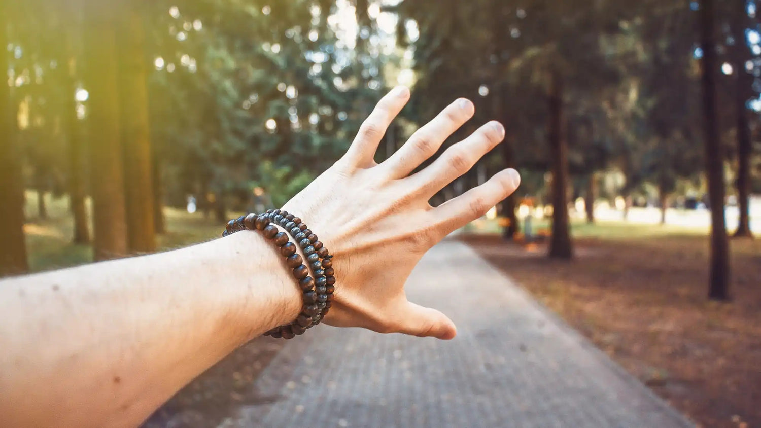 An arm and hand with two stacked beaded bracelets.