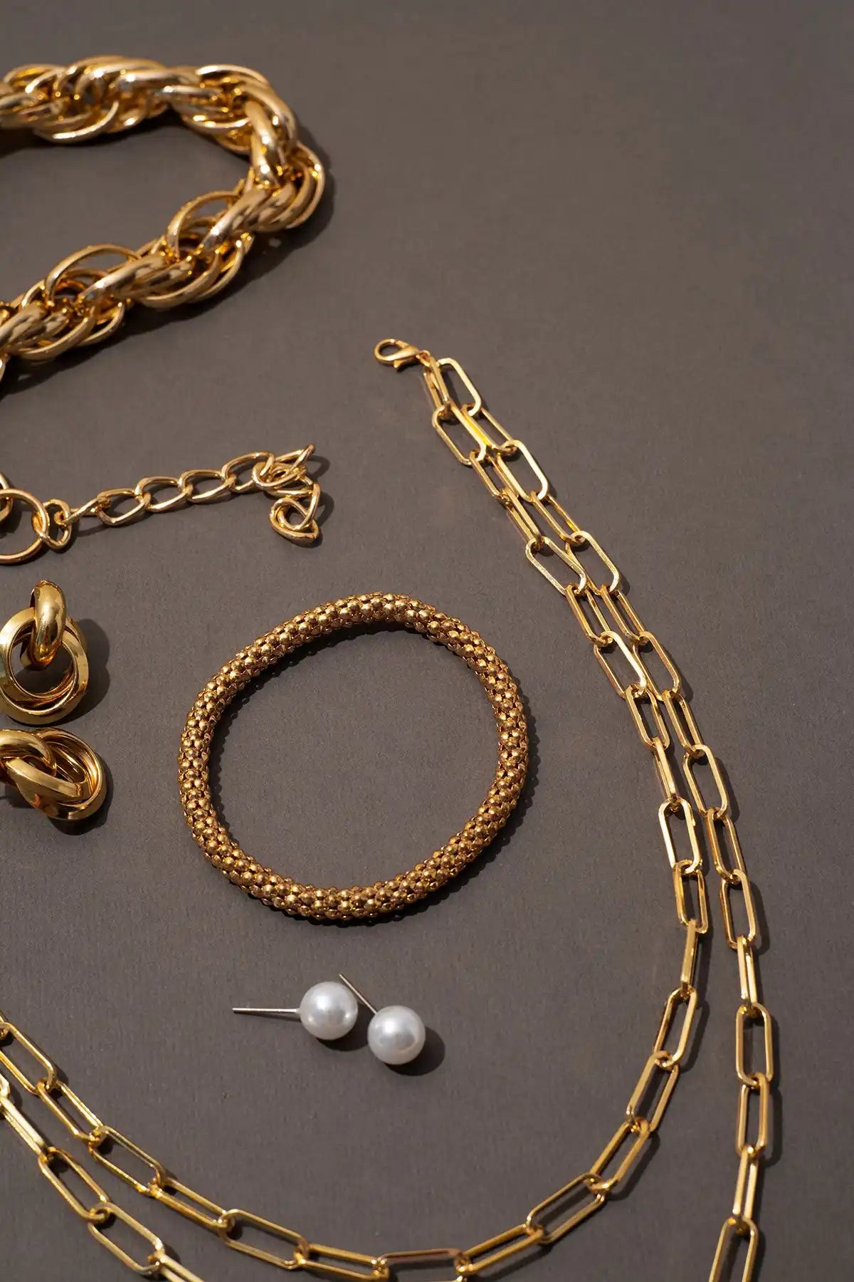 A collection of gold-toned jewelry including necklaces, bracelets, earrings, and pearl stud earrings.