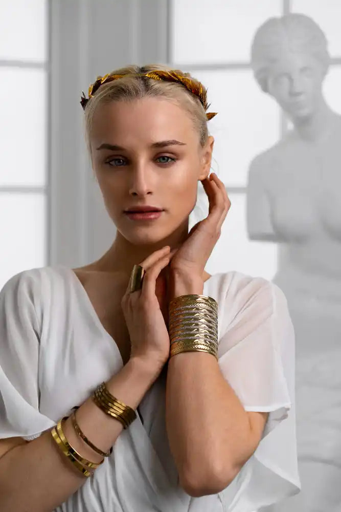 A woman with a gold leaf crown and gold bracelets.